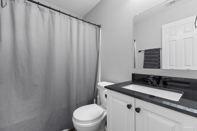 bathroom with vanity, toilet, and a textured ceiling