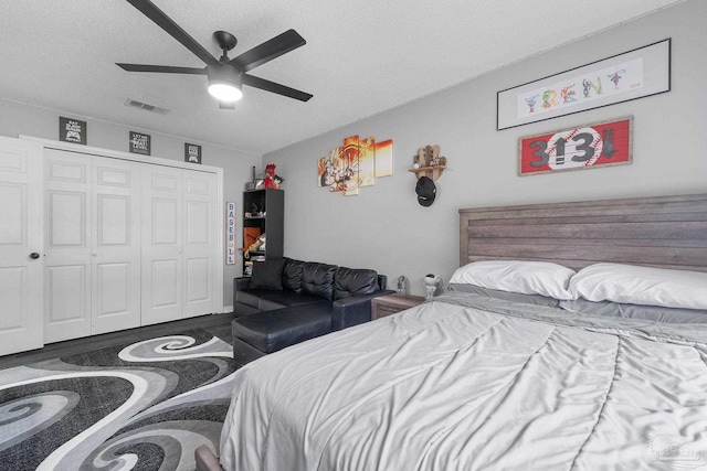 bedroom featuring ceiling fan, dark wood-type flooring, a closet, and a textured ceiling