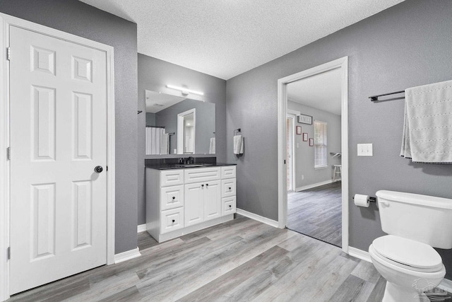 bathroom featuring vanity, a textured ceiling, wood-type flooring, and toilet