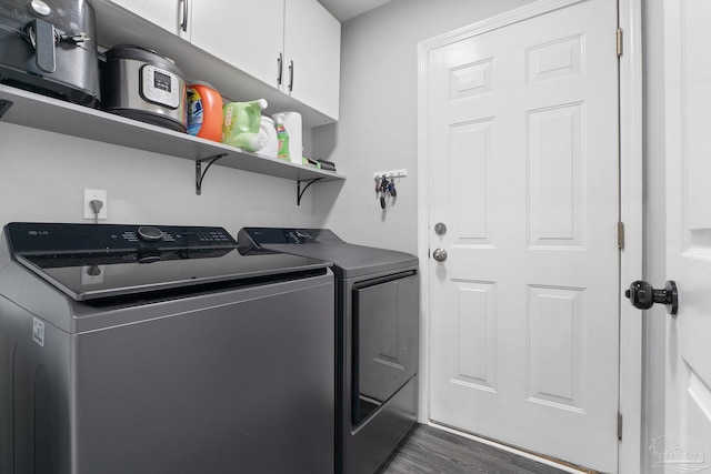 washroom with dark wood-type flooring, cabinets, and separate washer and dryer