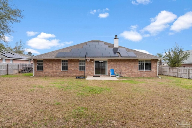 rear view of house featuring solar panels, a yard, and a patio area