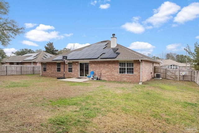 rear view of house with cooling unit, a lawn, a patio, and solar panels