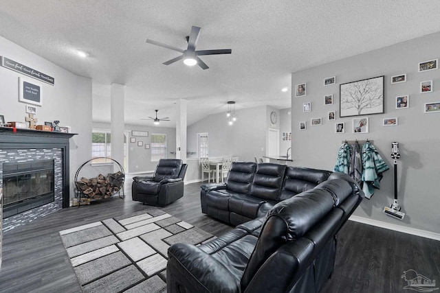 living room with ceiling fan, a fireplace, dark hardwood / wood-style flooring, and a textured ceiling