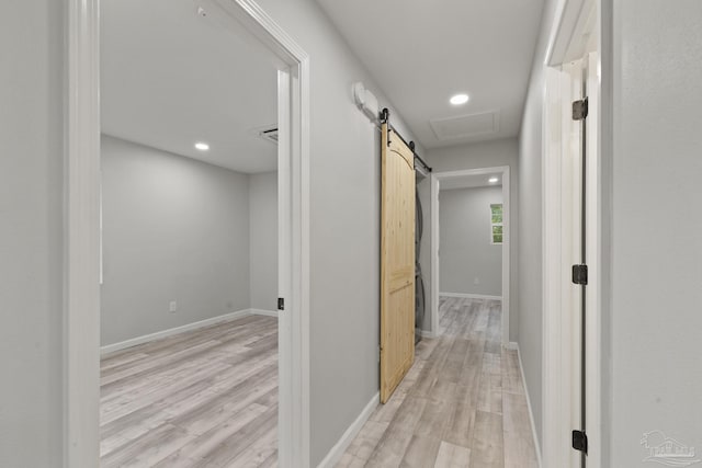 hall with a barn door and light hardwood / wood-style flooring