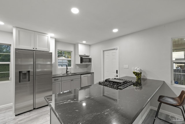 kitchen featuring sink, stainless steel appliances, kitchen peninsula, light hardwood / wood-style floors, and white cabinets