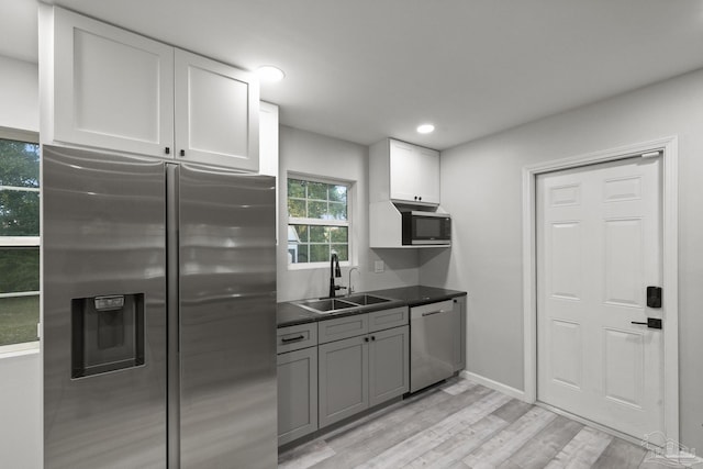 kitchen featuring sink, light hardwood / wood-style flooring, gray cabinets, white cabinetry, and stainless steel appliances