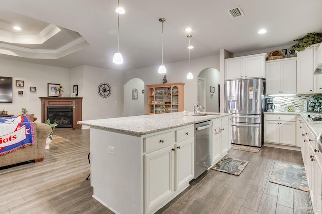 kitchen featuring stainless steel appliances, visible vents, a sink, arched walkways, and light wood-style flooring