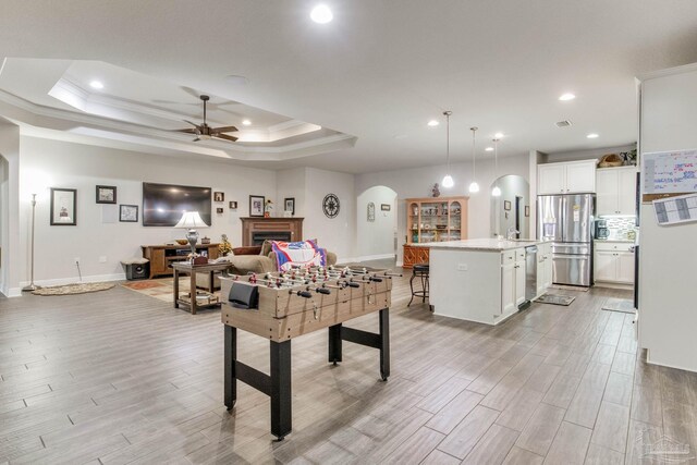 playroom with arched walkways, light wood finished floors, baseboards, and ceiling fan