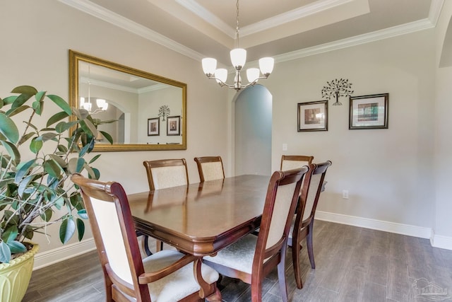 dining space with dark wood finished floors, arched walkways, a tray ceiling, and a chandelier