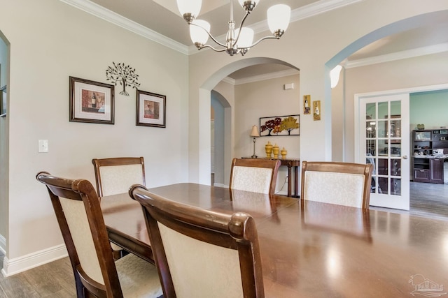 dining space featuring arched walkways, wood finished floors, baseboards, and ornamental molding