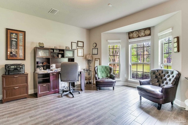 office with light wood-type flooring, baseboards, and visible vents