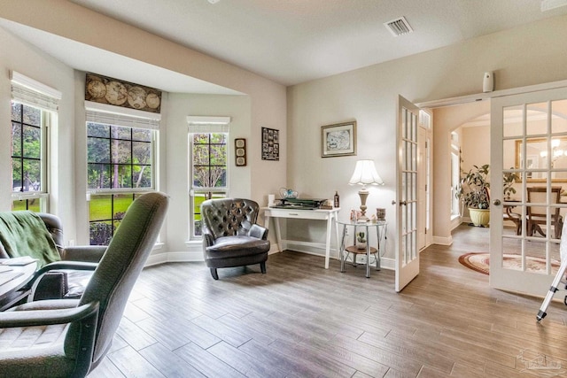 office area featuring visible vents, french doors, arched walkways, light wood-type flooring, and baseboards