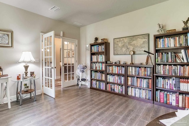 sitting room with wood finished floors, visible vents, baseboards, and french doors
