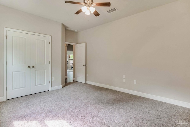unfurnished bedroom with a closet, ceiling fan, carpet, baseboards, and visible vents