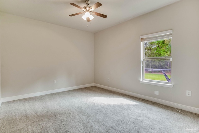 carpeted spare room featuring a ceiling fan and baseboards