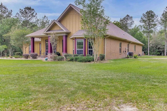 craftsman inspired home with a porch, a front yard, and central AC unit
