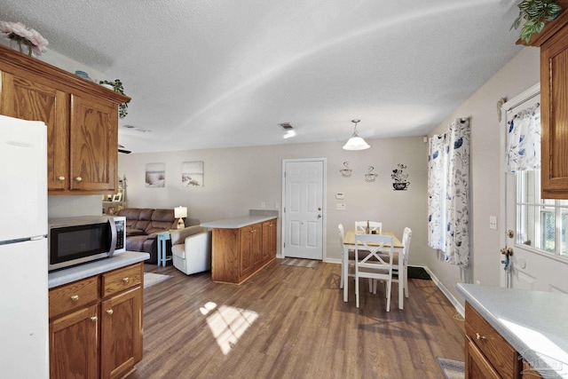 kitchen with pendant lighting, dark hardwood / wood-style floors, white fridge, and a textured ceiling