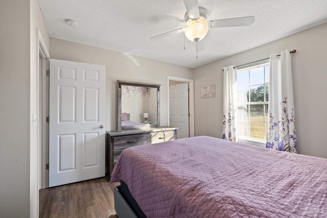 bedroom with a textured ceiling, ceiling fan, and dark hardwood / wood-style floors