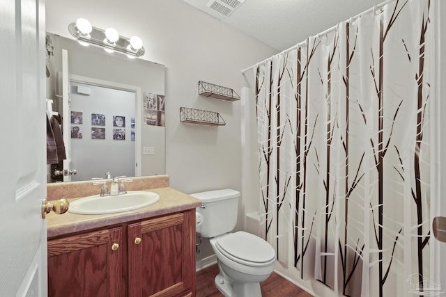 full bathroom featuring vanity, hardwood / wood-style flooring, toilet, shower / bathtub combination with curtain, and a textured ceiling