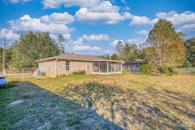 rear view of property with a yard, cooling unit, and a sunroom