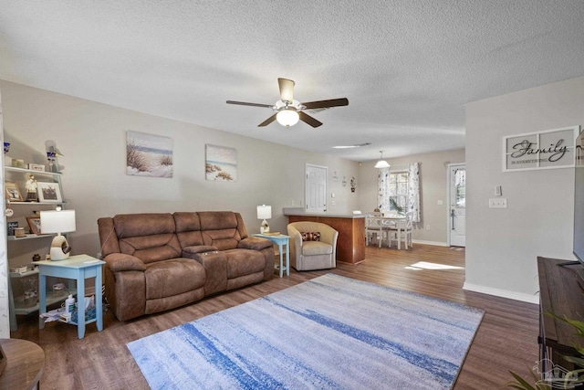 living room with ceiling fan, dark hardwood / wood-style flooring, and a textured ceiling