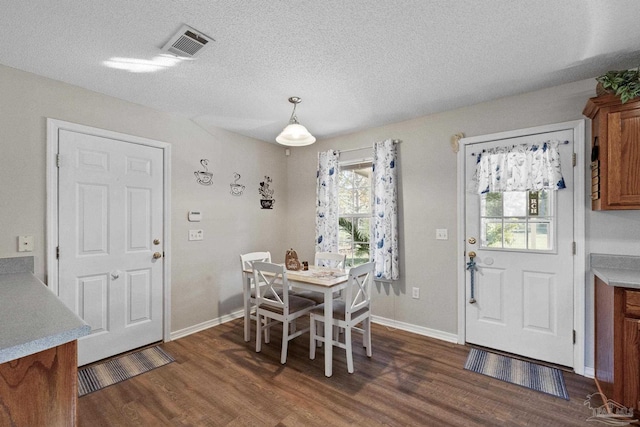 dining area with a textured ceiling and dark wood-type flooring