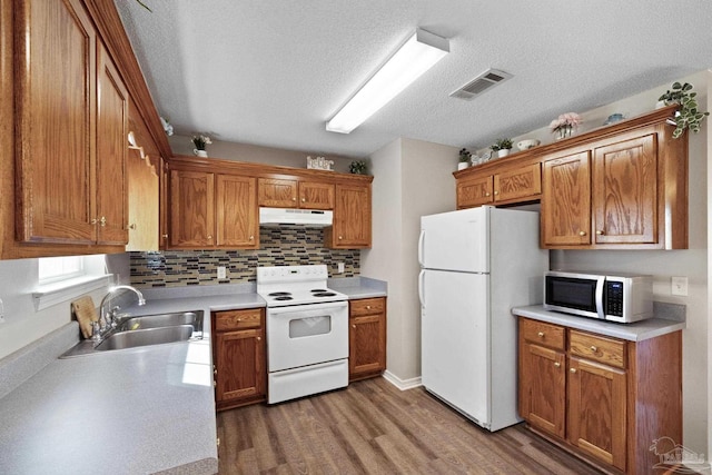 kitchen with sink, tasteful backsplash, wood-type flooring, a textured ceiling, and white appliances