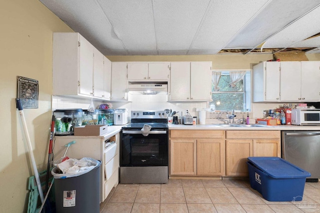 kitchen with appliances with stainless steel finishes, white cabinetry, sink, and light tile patterned floors