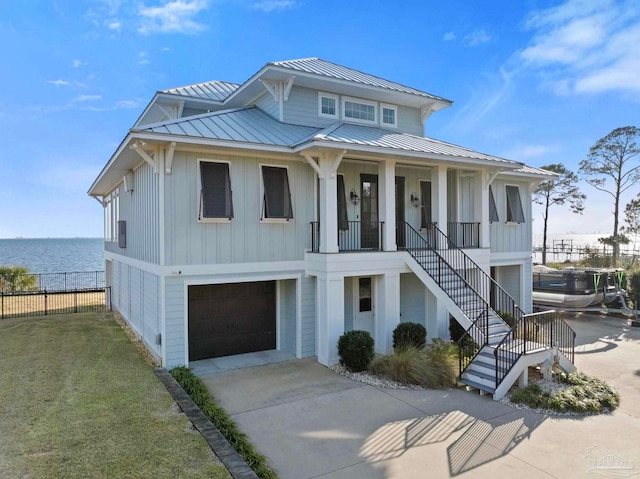 view of front of property featuring concrete driveway, a standing seam roof, stairs, a porch, and board and batten siding