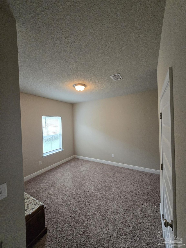 unfurnished room with visible vents, baseboards, a textured ceiling, and carpet flooring