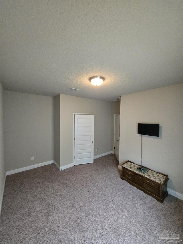 unfurnished living room with baseboards, carpet floors, and a textured ceiling