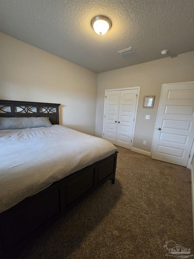 carpeted bedroom featuring a closet, visible vents, a textured ceiling, and baseboards