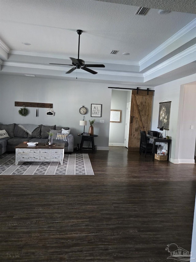 living room with visible vents, crown molding, a barn door, a tray ceiling, and a ceiling fan