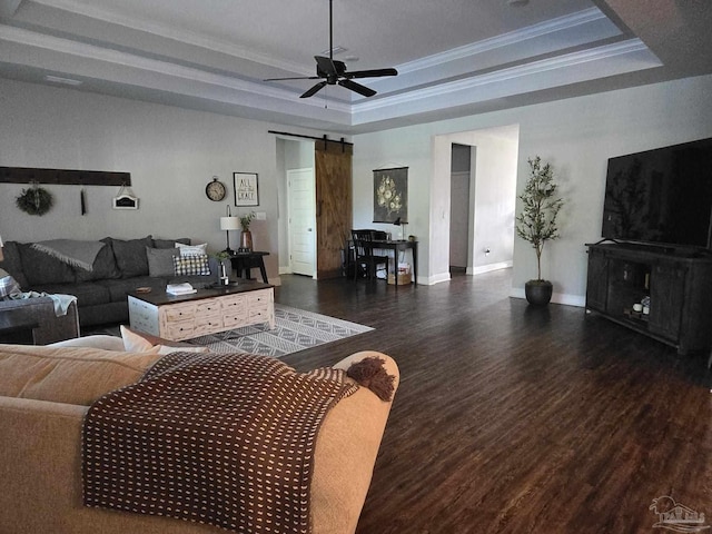 living room featuring ceiling fan, a barn door, ornamental molding, wood finished floors, and a raised ceiling