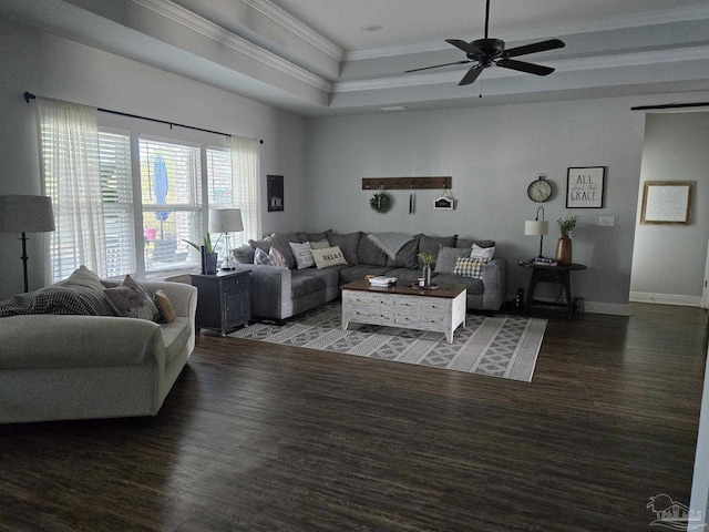 living area with ornamental molding, a tray ceiling, wood finished floors, baseboards, and ceiling fan