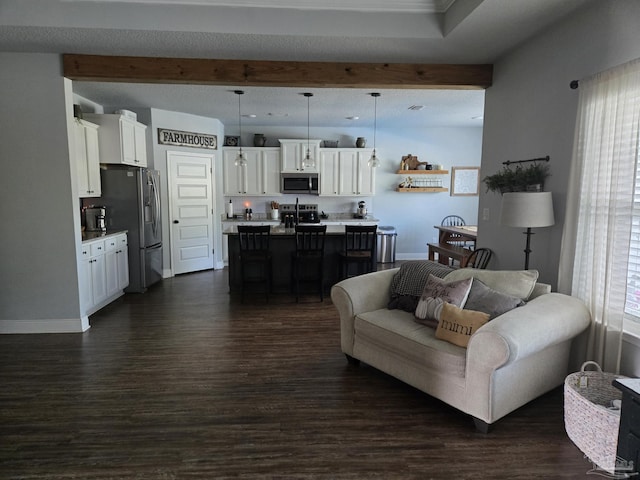 living room featuring a wealth of natural light, beamed ceiling, and dark wood finished floors