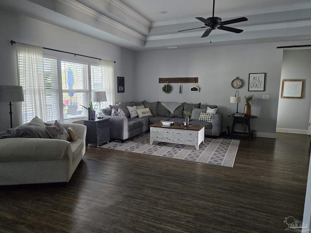 living room with ornamental molding, a ceiling fan, a tray ceiling, and wood finished floors