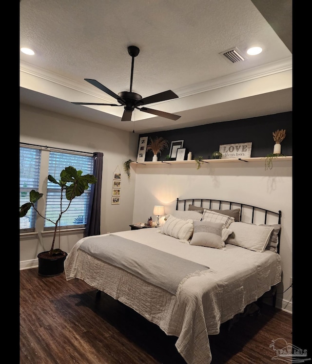 bedroom featuring visible vents, baseboards, ornamental molding, wood finished floors, and a textured ceiling