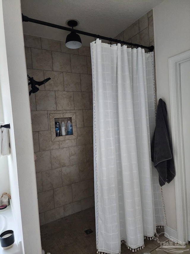 bathroom featuring a textured ceiling and a tile shower