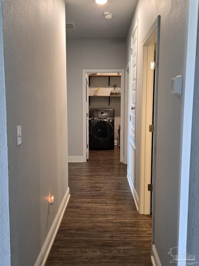 corridor with visible vents, baseboards, dark wood-type flooring, and washer / dryer