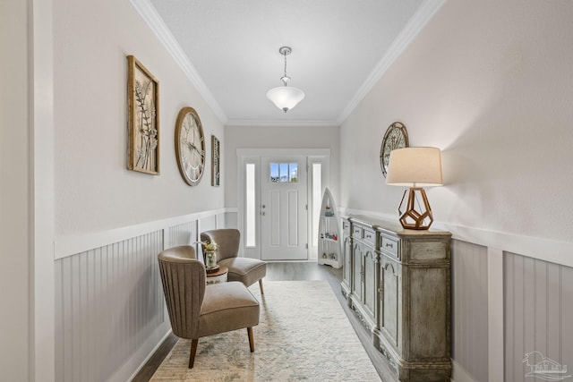 entrance foyer featuring a wainscoted wall, ornamental molding, and wood finished floors