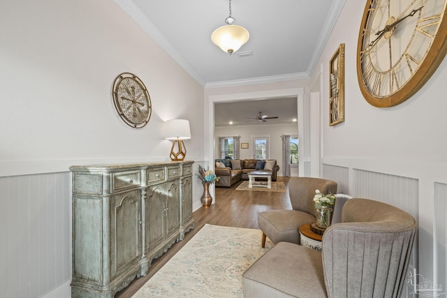 hall with crown molding, wood finished floors, and wainscoting