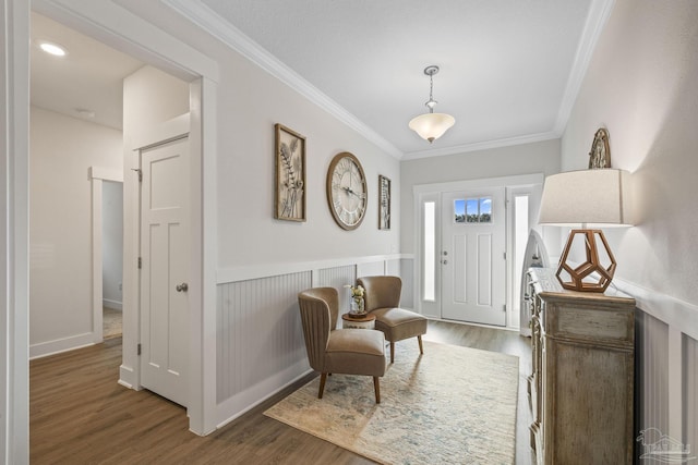 foyer entrance featuring a wainscoted wall, crown molding, and wood finished floors