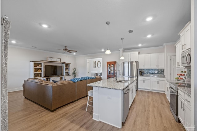 kitchen with light wood finished floors, a kitchen bar, appliances with stainless steel finishes, and decorative backsplash