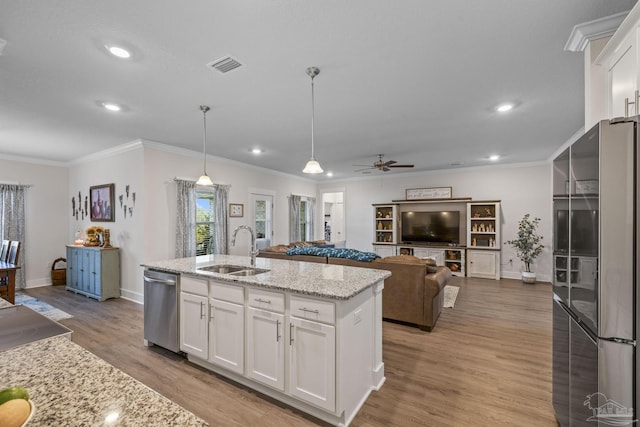 kitchen featuring visible vents, white cabinets, wood finished floors, stainless steel appliances, and a sink