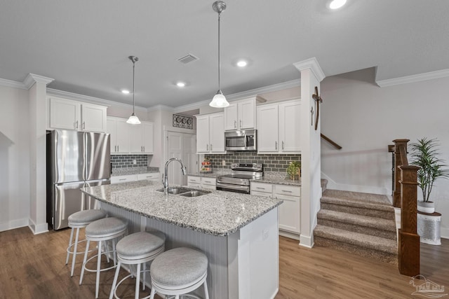 kitchen with visible vents, stainless steel appliances, a sink, and a kitchen breakfast bar