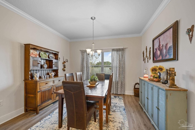 dining room with a chandelier, crown molding, light wood-style flooring, and baseboards