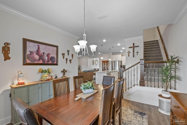 dining room with an inviting chandelier, stairs, ornamental molding, and wood finished floors