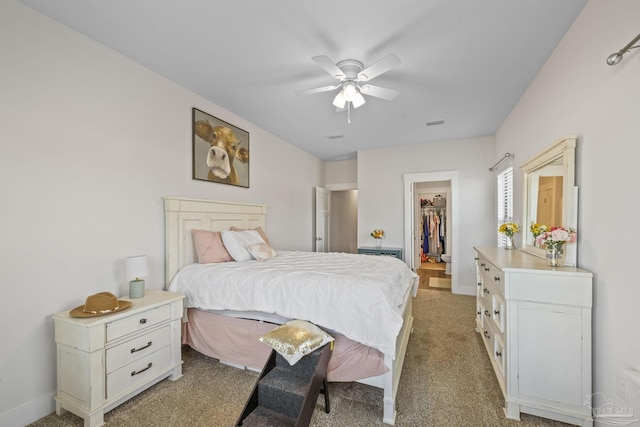 bedroom featuring light colored carpet, ceiling fan, a spacious closet, and baseboards