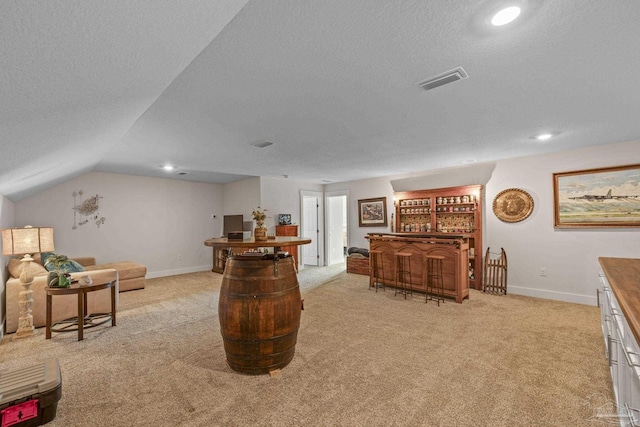 living area with visible vents, light carpet, a bar, and a textured ceiling